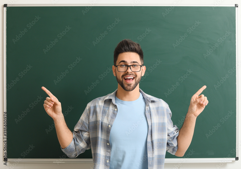 Male teacher near blackboard in classroom