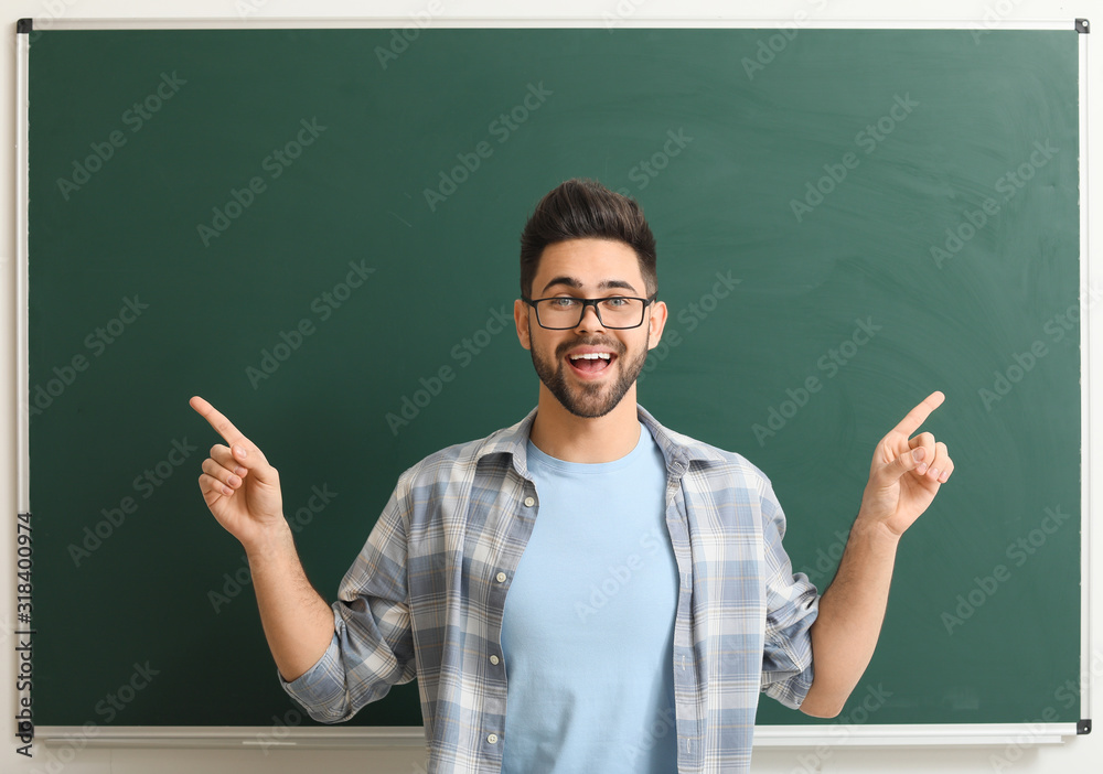 Male teacher near blackboard in classroom Male teacher near blackboard in classroom