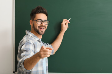 Male teacher writing on blackboard in classroom