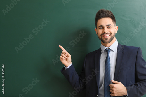 Obraz na plátne Male teacher near blackboard in classroom