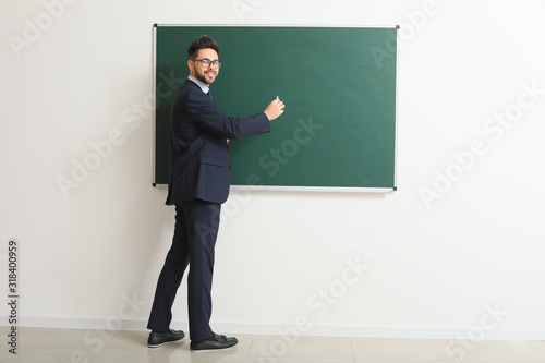 Male teacher writing on bla...