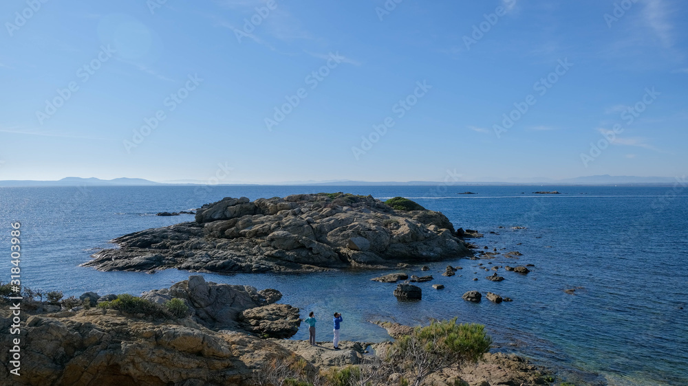 Tourists on a clear sunny winter day on the Mediterranean coast. Hiking trails near Roses. Picturesque landscapes, beautiful places. Winter holidays in Catalonia.