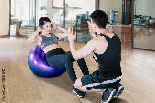 Personal trainer helping young woman doing workout