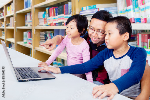 Two kids studying with their father with laptop