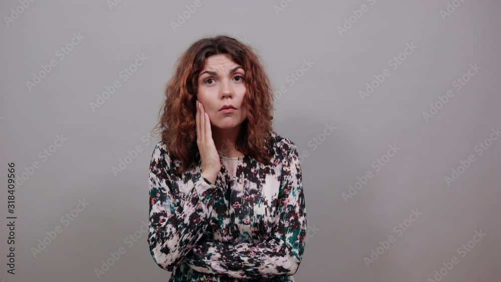 Unhappy charming young lady over isolated gray background in fashion shirt keeping hand on cheek, having toothache, having nice ring. People emotions. Lifestyle concept Unhappy charming young lady over isolated gray background in fashion shirt keeping hand on cheek, having toothache, having nice ring. People emotions. Lifestyle concept
