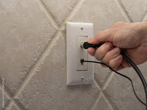 Cuadro en lienzo Male electrician connecting coax cable cord to wall outlet