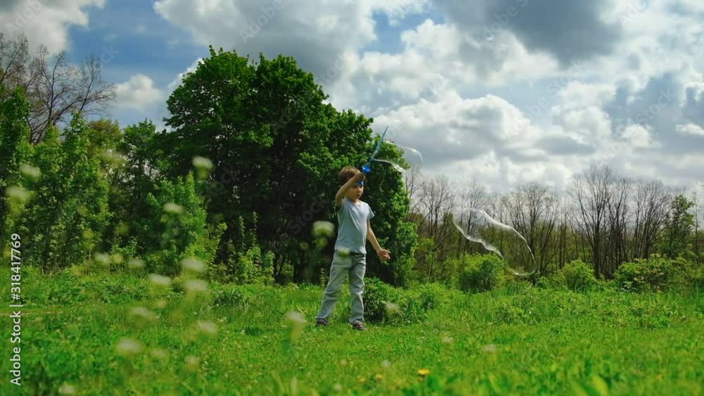 Slow motion. Little caucasian kid playing with soap bubble on spring meadow. Happy boy having fun outdoor. joy. Slow motion. Little caucasian kid playing with soap bubble on spring meadow. Happy boy having fun outdoor. joy.