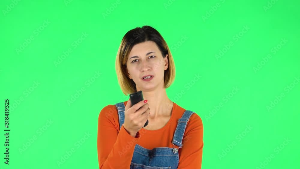 Woman with TV remote in her hand, switching on TV. Green screen Woman with TV remote in her hand, switching on TV. Green screen