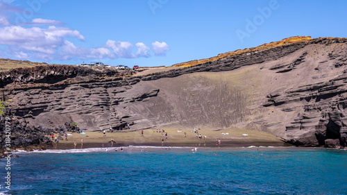 People on Papakōlea Beach - a green sand beach located near South Point, one of four green beaches in the world, Big Island, Hawaii.