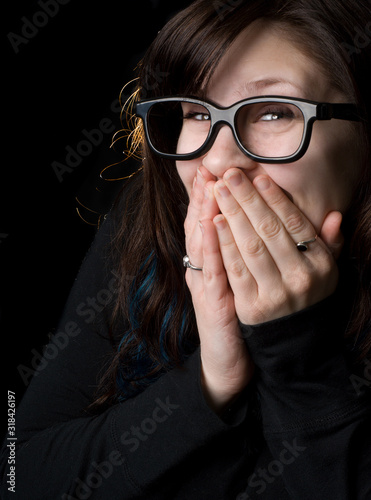 A dorky girl with goofy glasses on black background. photo