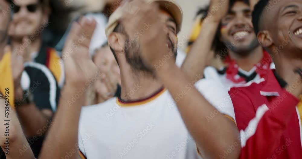 Excited sports fans at live game chanting and cheering for their team. German soccer team supporters watching football match and encouraging their national team.