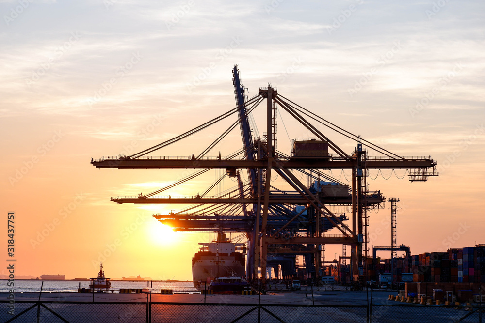 Container ship With cranes for loading goods in the port in the evening