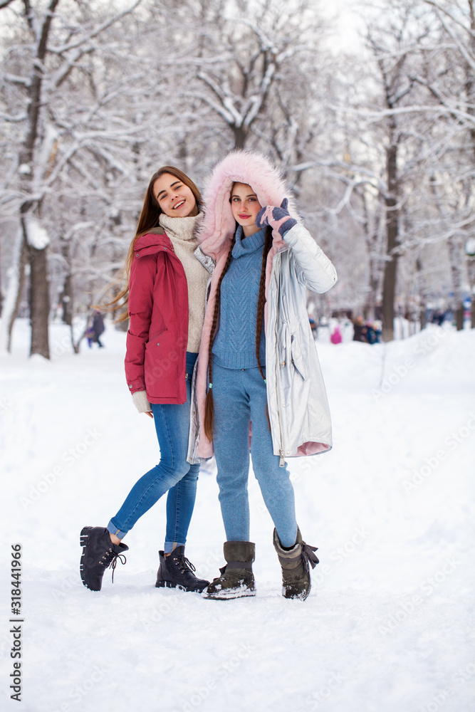 Portrait two young beautiful women walking in winter park