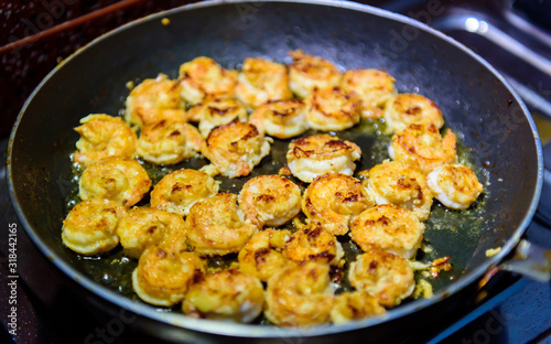 Process of roasting peeled shrimp with garlic in a frying pan, close-up. Prawns golden fried. Seafood delicious.
