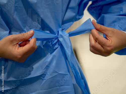 Fototapete Tying blue medical gown before a procedure
