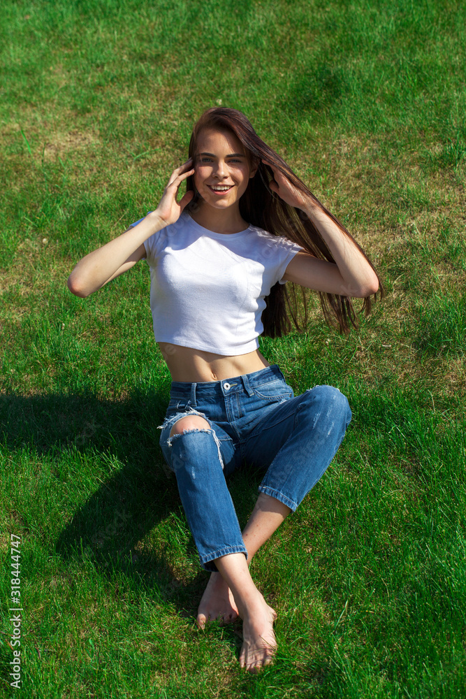 Fototapeta premium Portrait of a young beautiful girl resting on the lawn in the park