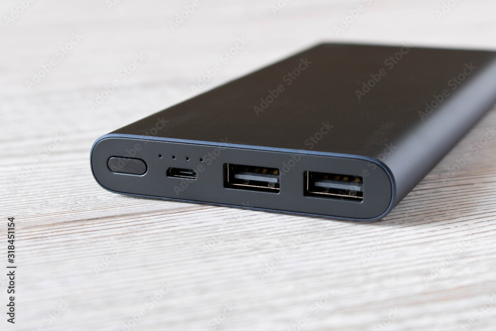 Black power Bank for charging mobile devices on wooden table. Black power Bank for charging mobile devices on wooden table.