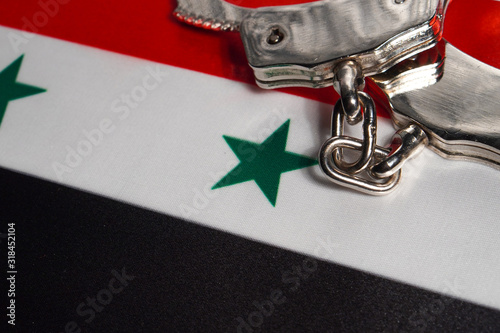 Handcuff on the flag of Syria. Close-up, copy space