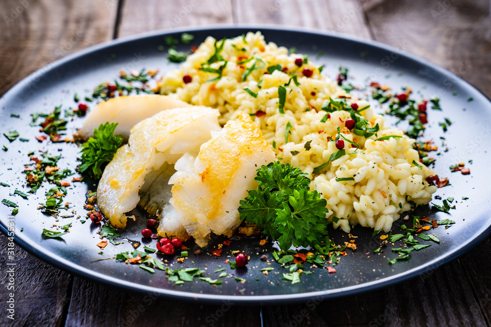 Risotto with fried cod loin on wooden background Risotto with fried cod loin on wooden background