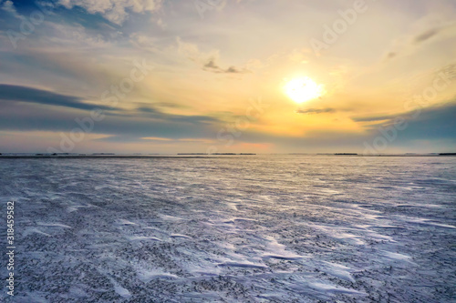 Frozen Canadian winter landscape with sun traveling low in the sky with lots of blowing snow.