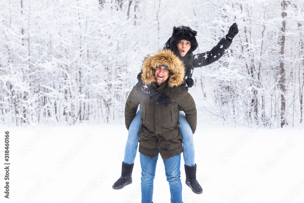 Fototapeta premium Portrait of happy young couple in winter park with their friend behind