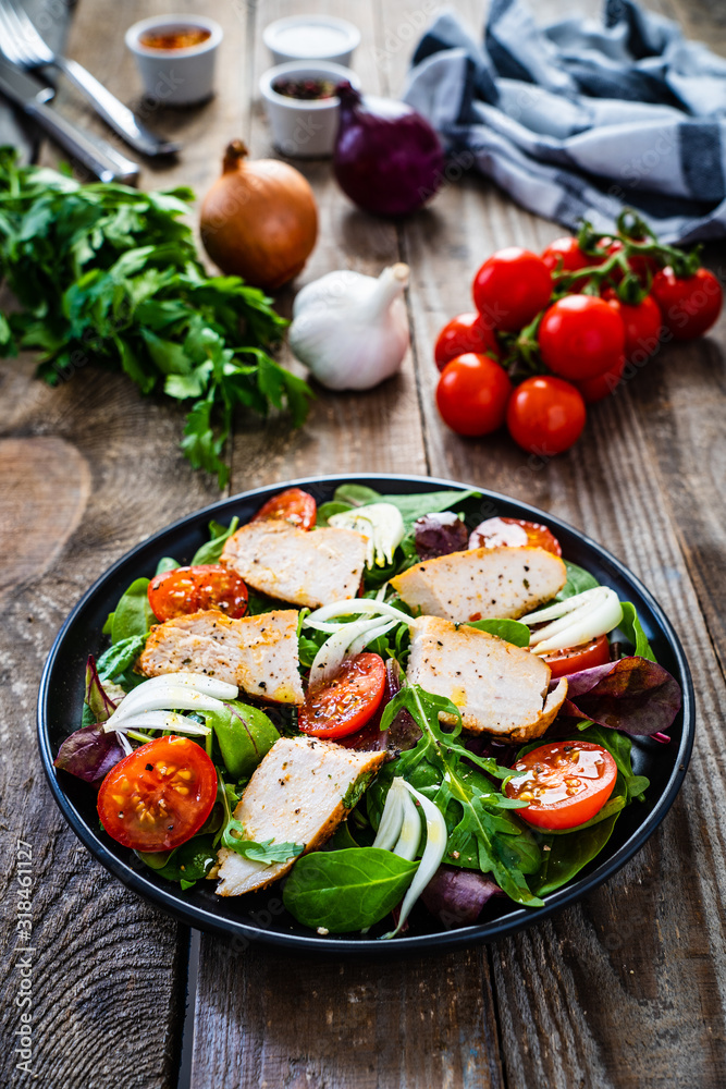 Caesar salad - barbecue chicken breast and vegetables on wooden table