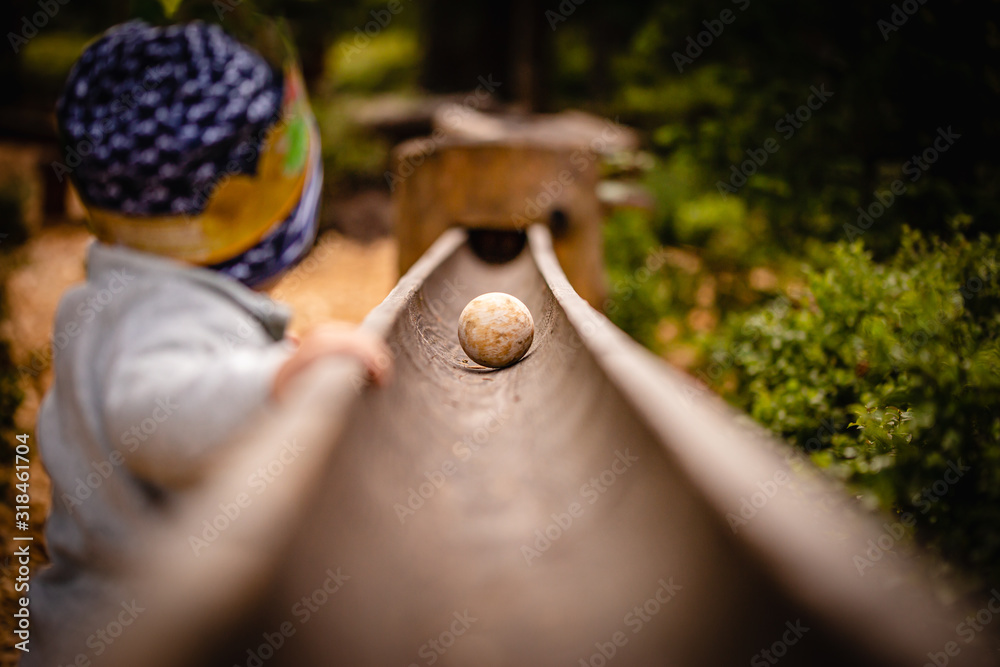 Small Child standing at a big wooden ball path in the Zillertal, Austria in the alps.