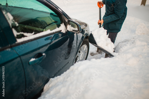 a man digs the car from the snow. the car was covered in snow. push the snow away from the car