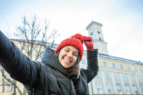 woman taking selfie on her phone lviv city hall on background