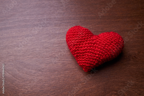 red heart made from wool on a dark wooden background. copy space. romance and valentine day concept.