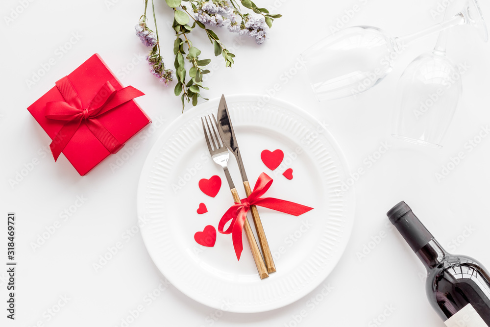 Romantic dinner on Valentines Day. Wine, plate, present box on white background top-down Romantic dinner on Valentines Day. Wine, plate, present box on white background top-down