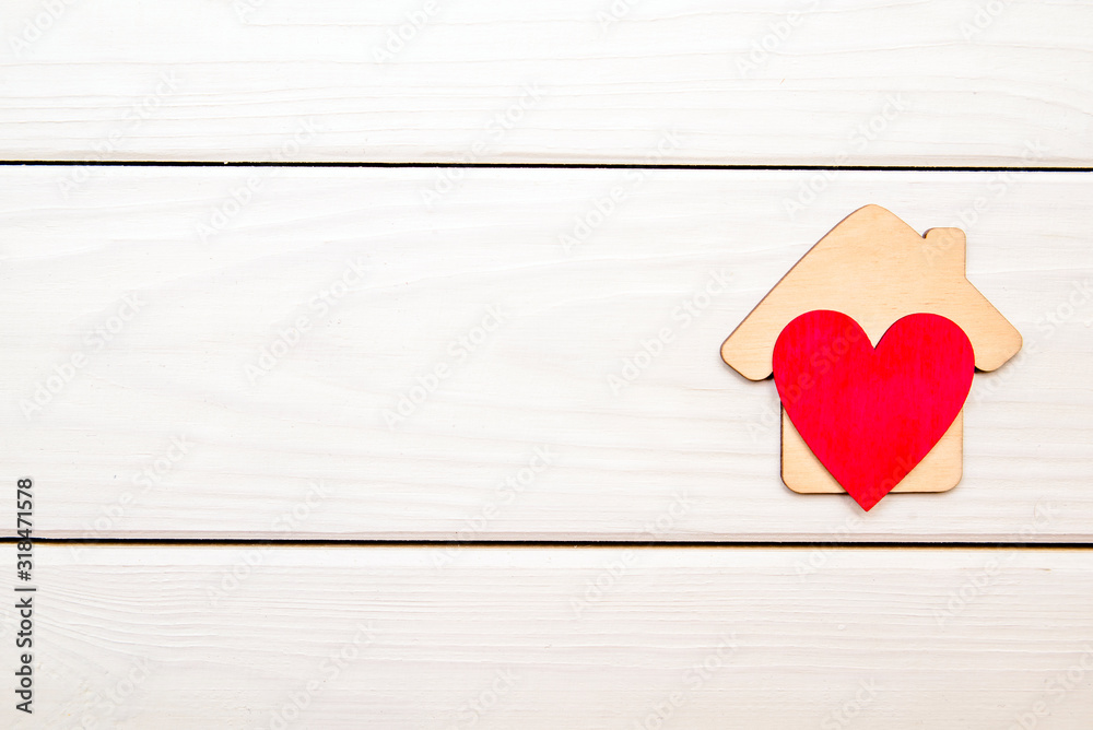 The symbol of the house with heart on wooden background The symbol of the house with heart on wooden background