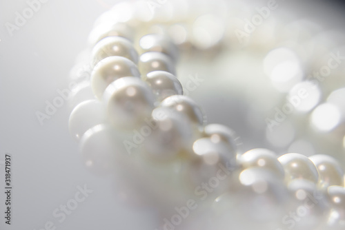 A necklace of pearls lying on white glass