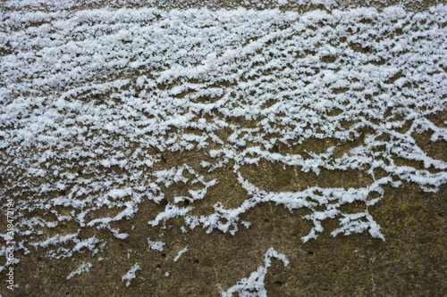 Beautiful snow with lots of snowflakes laid out on a loose concrete surface with interesting and bright patterns.