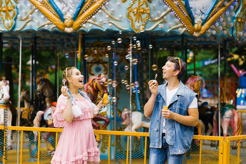 A beautiful bright cheerful romantic couple in love enjoy soap bubbles in an amusement Park © Sunshine
