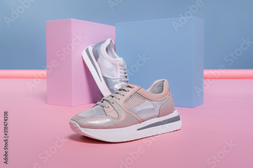 female sneakers of different colors, but of the same model, stand on a pink, blue stand from the studio. Promotional photo