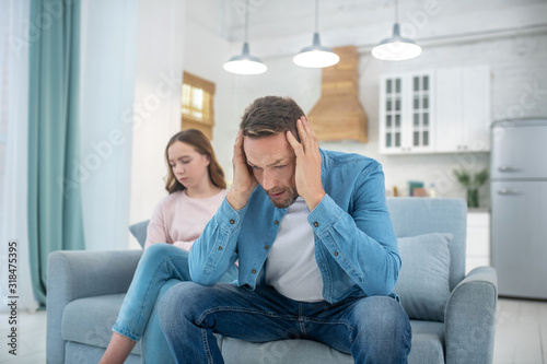 Pensive father and sad daughter sitting on couch.