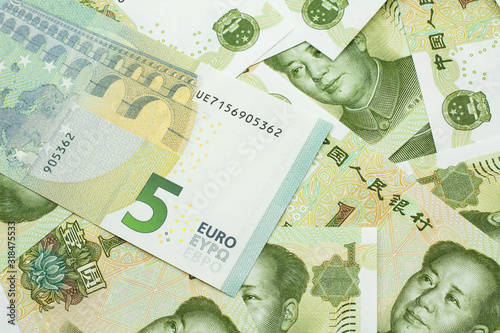A close up image of a five Euro bank note from Europe in macro with a bed of Chinese one yuan bank notes
