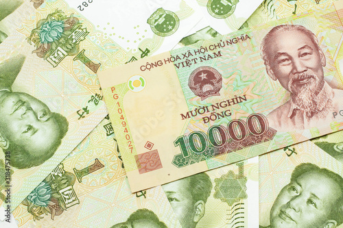 A close up image of a Vietnamese ten thousand dong bank note on a background of Chinese one yuan bills in macro
