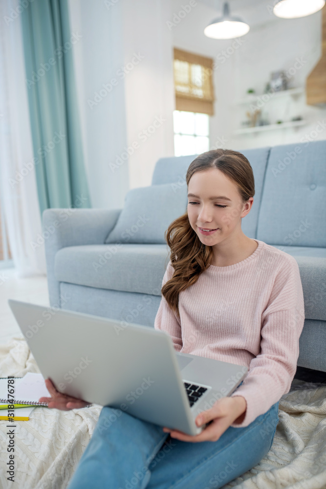 Naklejka premium Happy girl with laptop sitting on the floor at home.