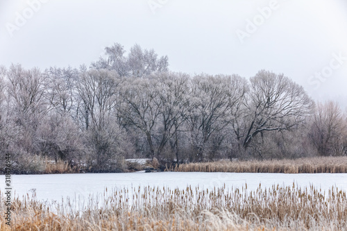 Winter landscape with frozen pond covered with snow. Central european countryside. Christmas winter concept