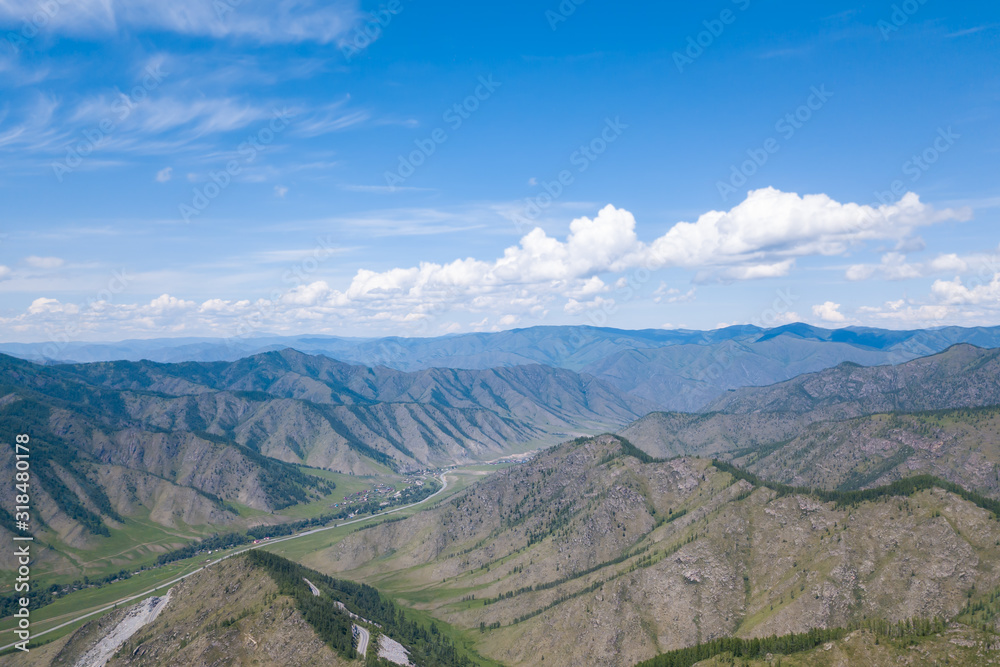 Aerial panoramic wide banner view of a Chike-Taman pass in the Altai mountains with green trees, Blue sky and clouds.