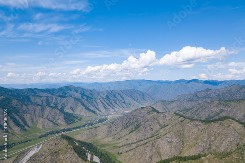 Aerial panoramic wide banner view of a Chike-Taman pass in the Altai mountains with green trees, Blue sky and clouds.