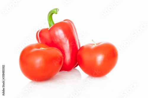Two red tomatoes and one pepper, green natural delicious and appetizing vegetables grown in China on a white isolated background. Healthy foods in stores.