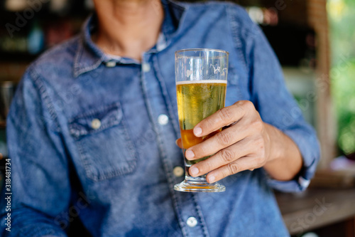 A man wearing a denim shirt and a glass of beer in the bar 