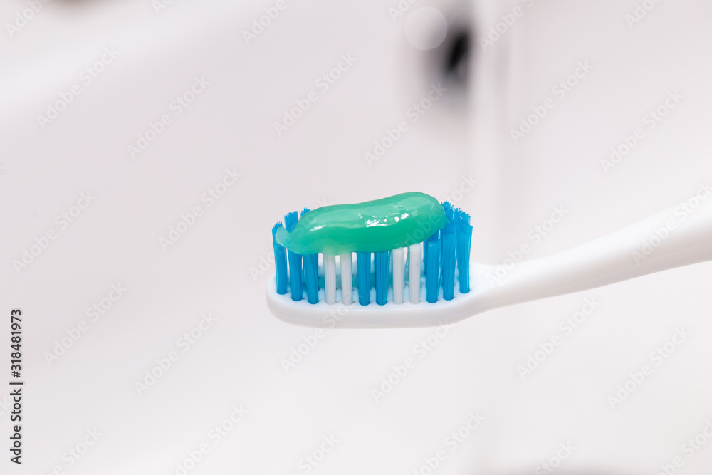 Toothbrush with toothpaste in the guy's hand on the background of the washbasin. Toothbrush with toothpaste in the guy's hand on the background of the washbasin.