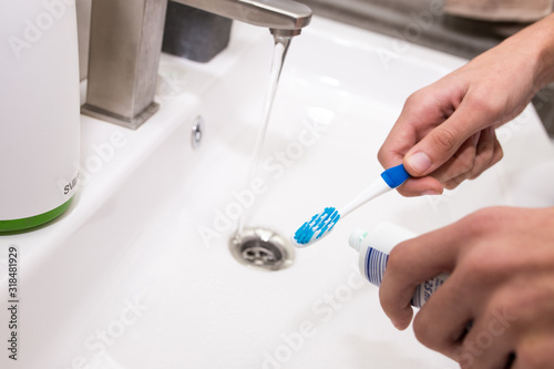 Toothbrush with toothpaste in the guy's hand on the background of the washbasin. © vfhnb12