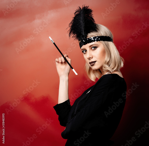 Beautiful blonde woman in twenties years clothes with smoking pipe on red background