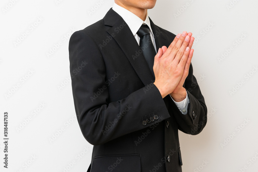 喪服で手を合わせる男性