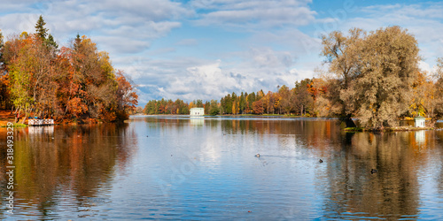 Panorama of beautiful autumn park with pond on clear day